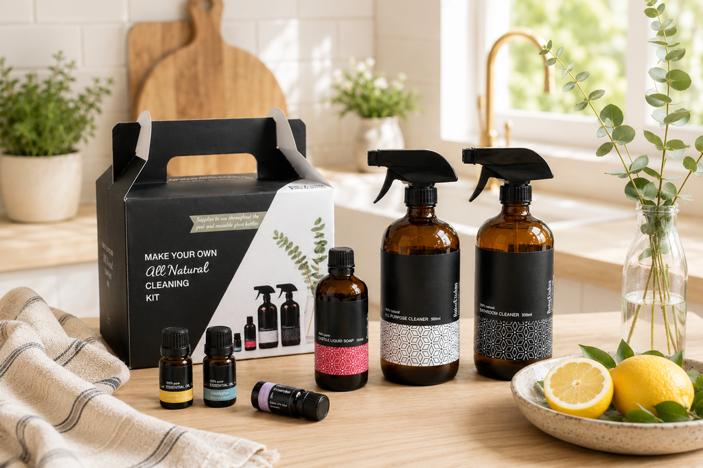RetroKitchen Make your own all natural cleaning kit. Set of natural cleaning products including bottles, boxes, and essential oils on a wooden surface with lemons and plants in the background.